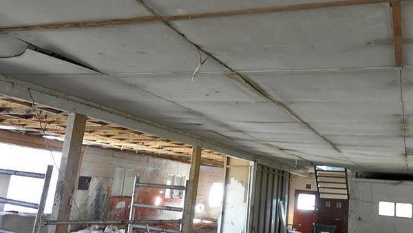Bildet viser et rom som er under rehabilitering. Vegger og himlingsplater er delvis fjernet. Den ene delen av taket består av gråhvite himlingsplater som inneholder asbest.