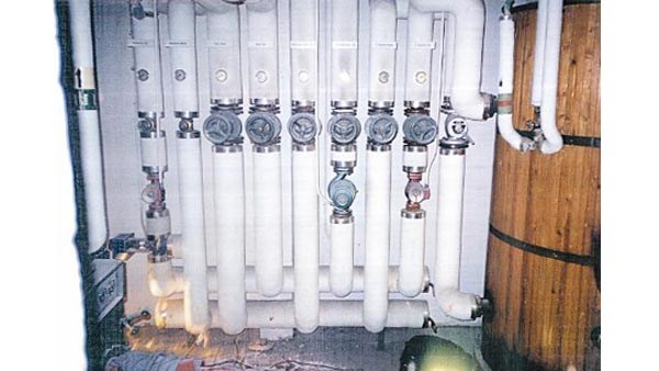 Bildet viser et rom mange mange hvitmalte rør med flere kraner på.