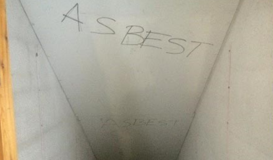 Bildet viser en trappeoppgang hvor ordet "asbest" er skrevet i himlingen.