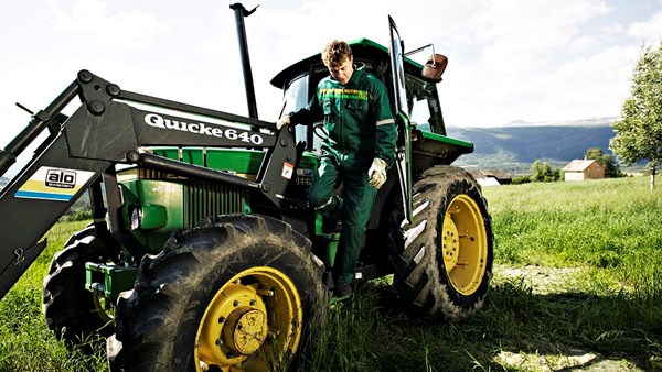Bildet viser en mann som går ut av en traktor. Foto.