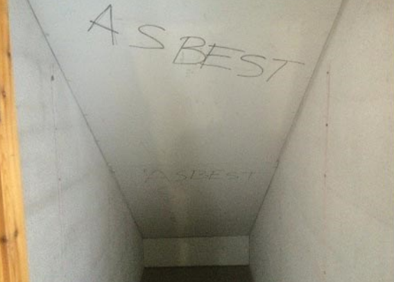 Bildet viser en trappeoppgang hvor ordet "asbest" er skrevet i himlingen.
